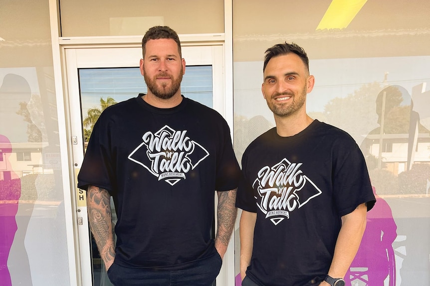 Two men wearing black T-shirts are standing in front of the store.