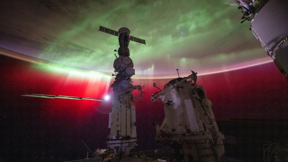 The aurora on Earth as seen from the space station. Different space models are in front