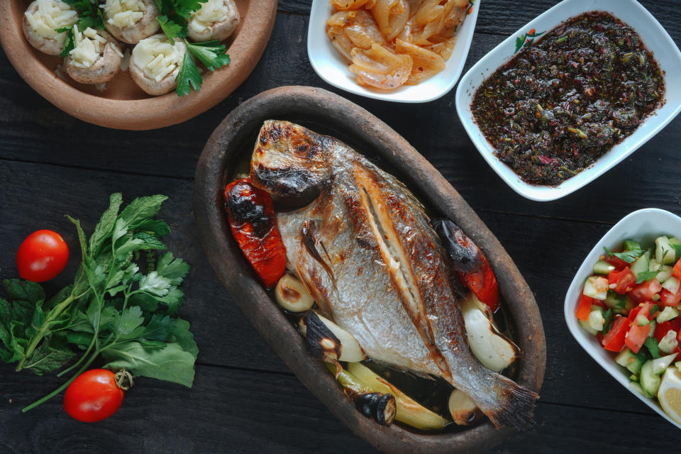 Fresh fish on a black wooden board. Raw uncooked sea bream on a black plate.