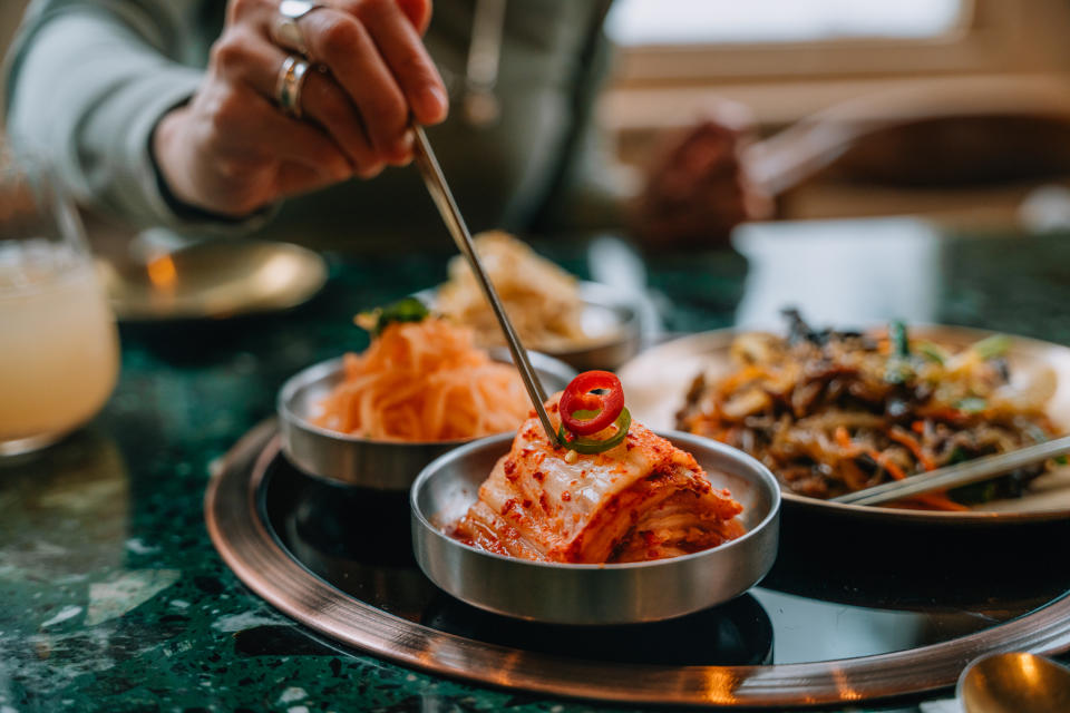 A woman enjoys traditional Korean fermented vegetables (banchan). Korean food and culture.