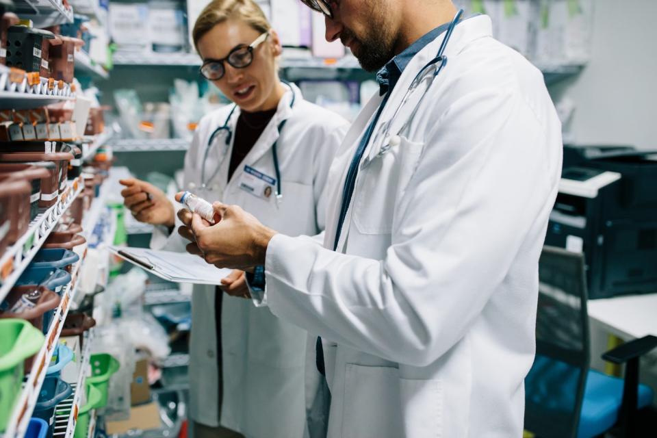 Two pharmacists look into a glass.